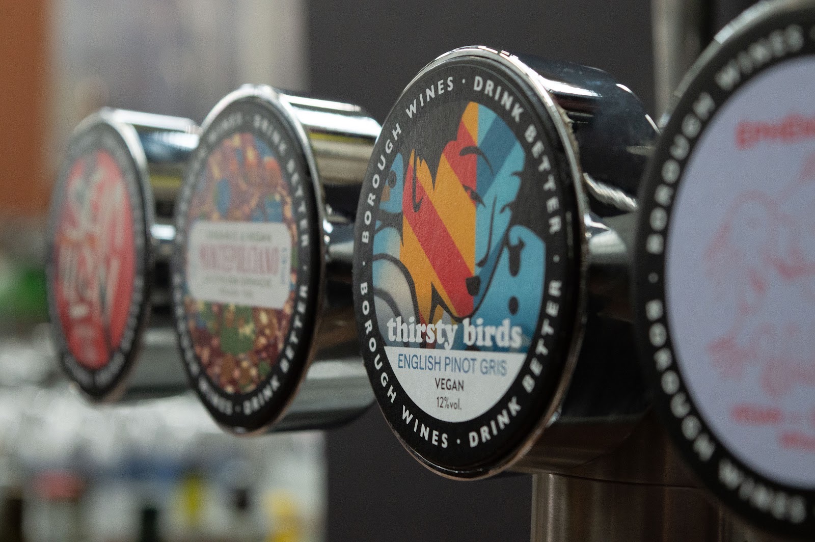 Close-up of the wine-tap badges reading Borough Wines, Drink Better, including a Thirsty Birds English Pinot Gris.